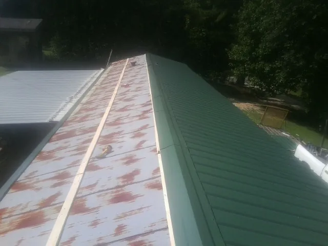 Old rusted panels beside newly installed green metal roofing — Wind Damage Roof Repair by Roofing Brothers in Taneytown