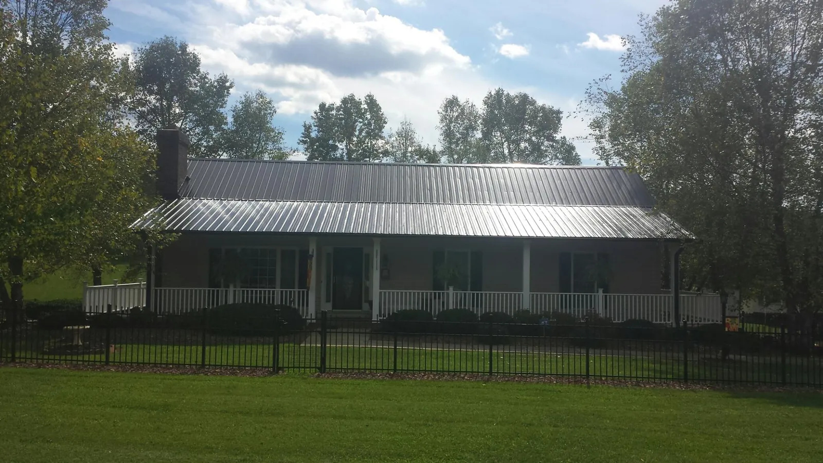 Gray metal roof on a brick ranch with a full width front porch — Gutter Guard Installation work by our crew in Taneytown