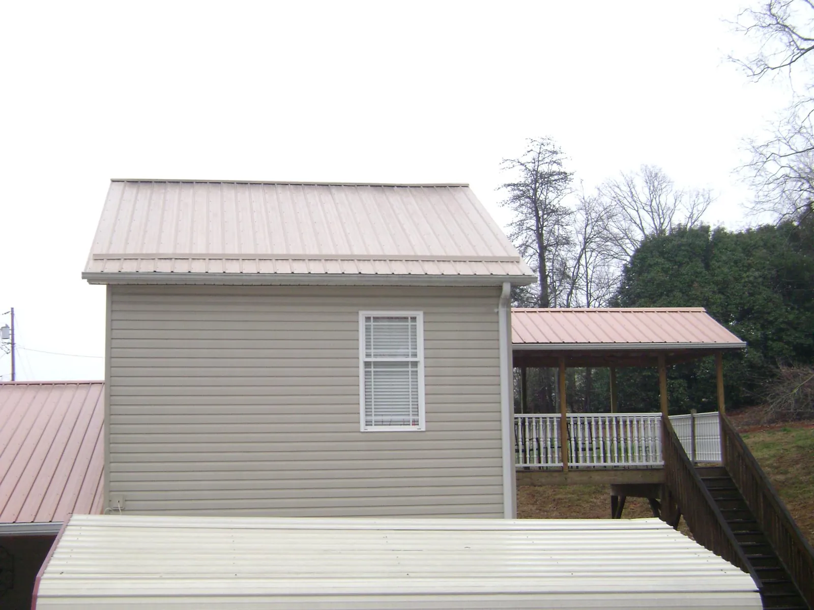 Tan metal roofs on a two story addition and attached porch, from a Roof Replacement job in Taneytown